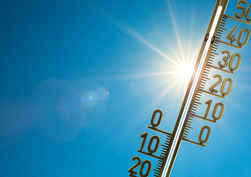 Thermometer vor blauem Himmel und Sonnenlicht