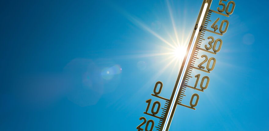 Thermometer vor blauem Himmel und Sonnenlicht
